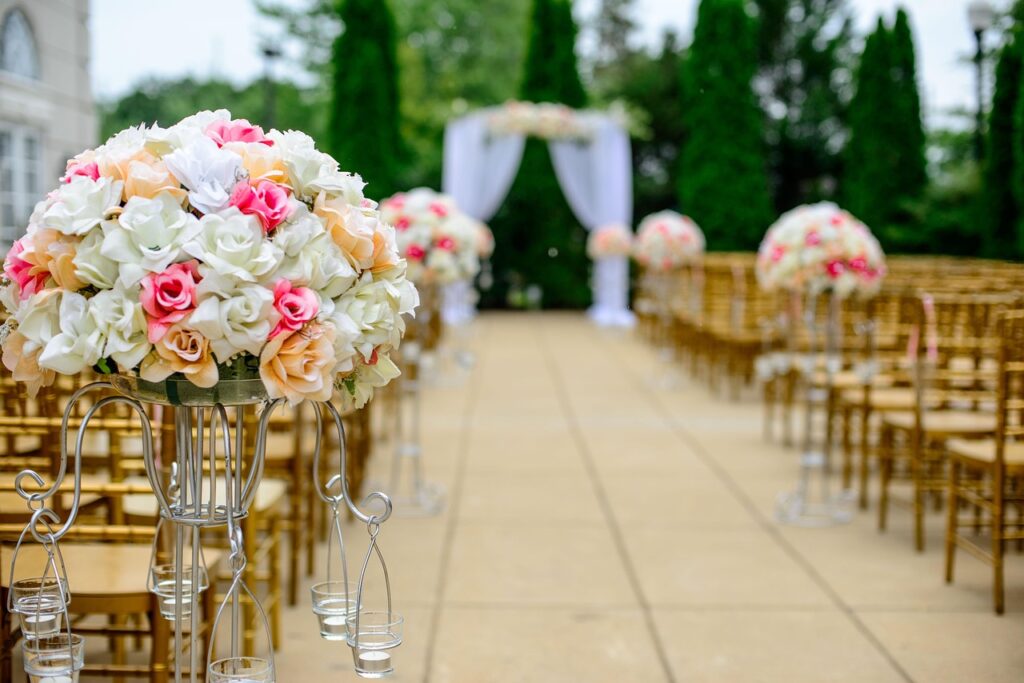 An outdoor minimalist wedding setting decorated with white flowers, arch with soft draped fabric and sleek wooden benches